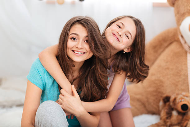 istock Two happy lovely sisters sitting and hugging at home 518470958