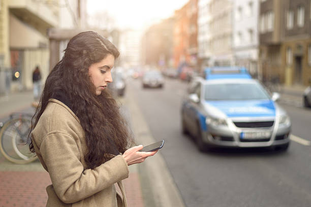 istock Brunette woman texting while standing by busy street 518472100