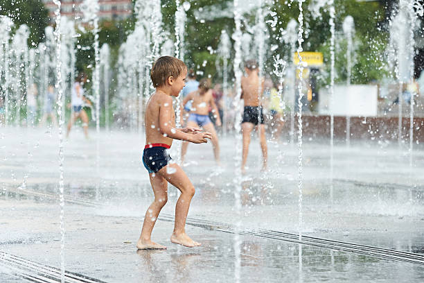 istock Happy kid playing in a fountain 518474461