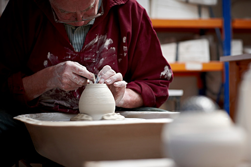 Senior man making a pot on a pottery wheel