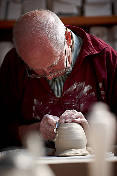 istock Potter shaping a jar base on spinning wheel 518482739