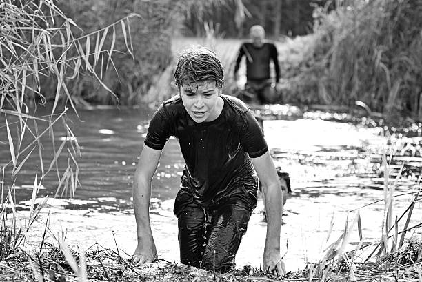 istock Father and son crossing water obstacle at mud run event 518483813