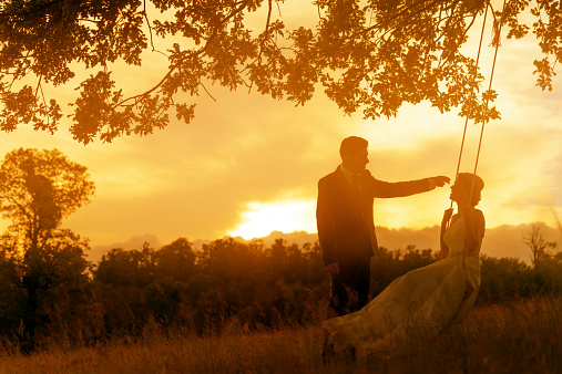 romantic grooms in sunset time on swing spending time.