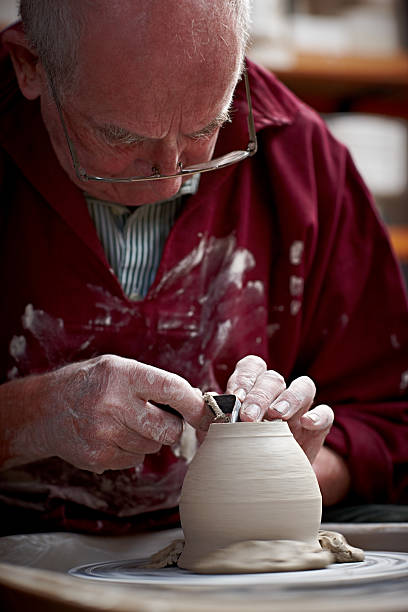 istock Elderly man shaping jar base on spinning wheel 518484507