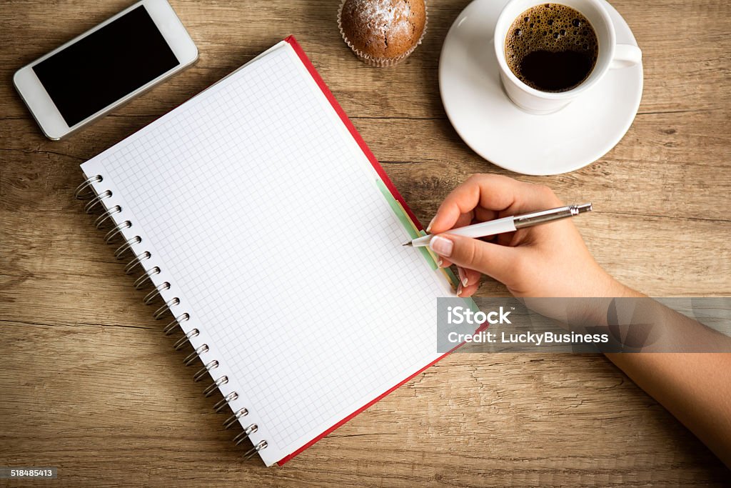 Making notes on coffee break Making notes on coffee break, female hand with pen Business Stock Photo