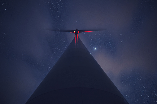 A wind turbine spins into the night.  Long exposure with light painting.