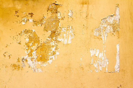 An old Sicilian wall background with a rough yellow peeling texture. Shot in Sicily, Italy.