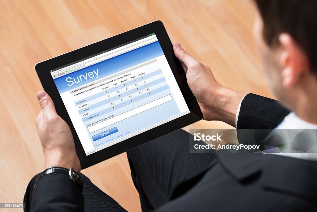 Businessman Looking At Online Survey Form Close-up Of Businessman Looking At Blank Online Survey Form On Digital Tablet Adult Stock Photo