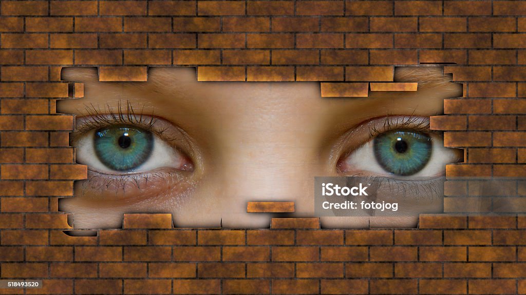 Eyes behind a wall Womans eye peeking through a hole in wall Crime Stock Photo