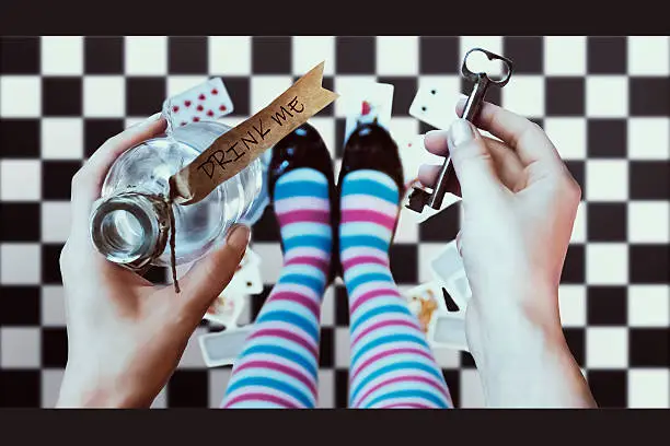 Alice in wonderland. Background. A key and a potion in hands against a chess floor