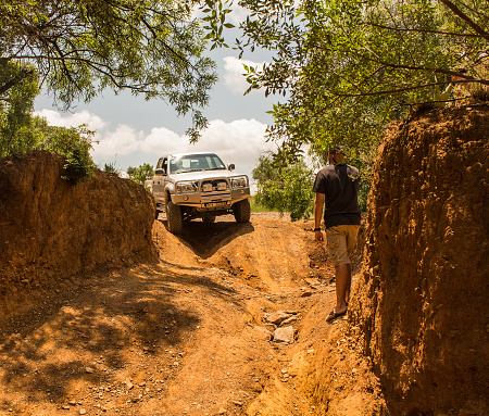 South Africa, Gauteng - February 06, 2016. Four-wheel drive vehicle Toyota Hilux is doing off-road trail with unidentified man assistance.