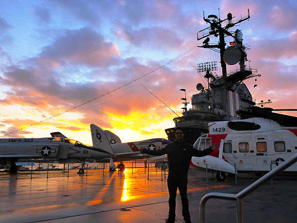 Visit to The Aerospace Museum of NY - The Intrepid New York, USA,  - November 8, 2013: Photographs taken on a visit to the public area of the aerospace museum of New York - The Intrepid. In this image we see an old plane in focus, with an old helicopter in the foreground and the control tower Aircraft Carrier Intrepid with the sunset in the background, causing a beautiful effect of light and shadow in the twilight angung rai museum of art stock pictures, royalty-free photos & images