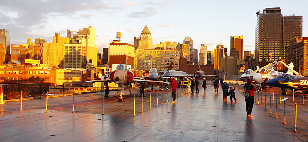 Visit to The Aerospace Museum of NY - The Intrepid New York, USA,  - November 8, 2013: Photographs taken on a visit to the public area of the aerospace museum of New York - The Intrepid. In this image we see anonymous strolling and watching the old planes exhibited with the City of New York in the background at dusk angung rai museum of art stock pictures, royalty-free photos & images