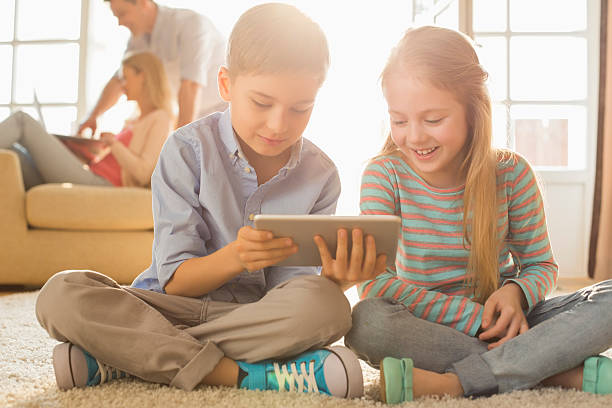 デジタルタブレットを使用して幸せな兄弟階 - digital tablet looking child offspring ストックフォトと画像