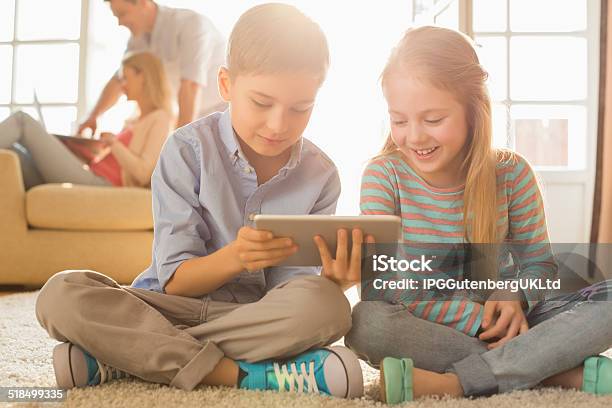 Happy Siblings Using Digital Tablet On Floor Stock Photo - Download Image Now - 8-9 Years, Boys, Digital Tablet