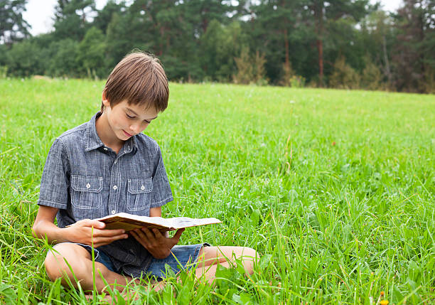 istock Child reading book outdoor 518500179