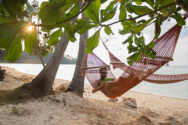 istock Man with digital tablet on hammock in tropical place 518503659