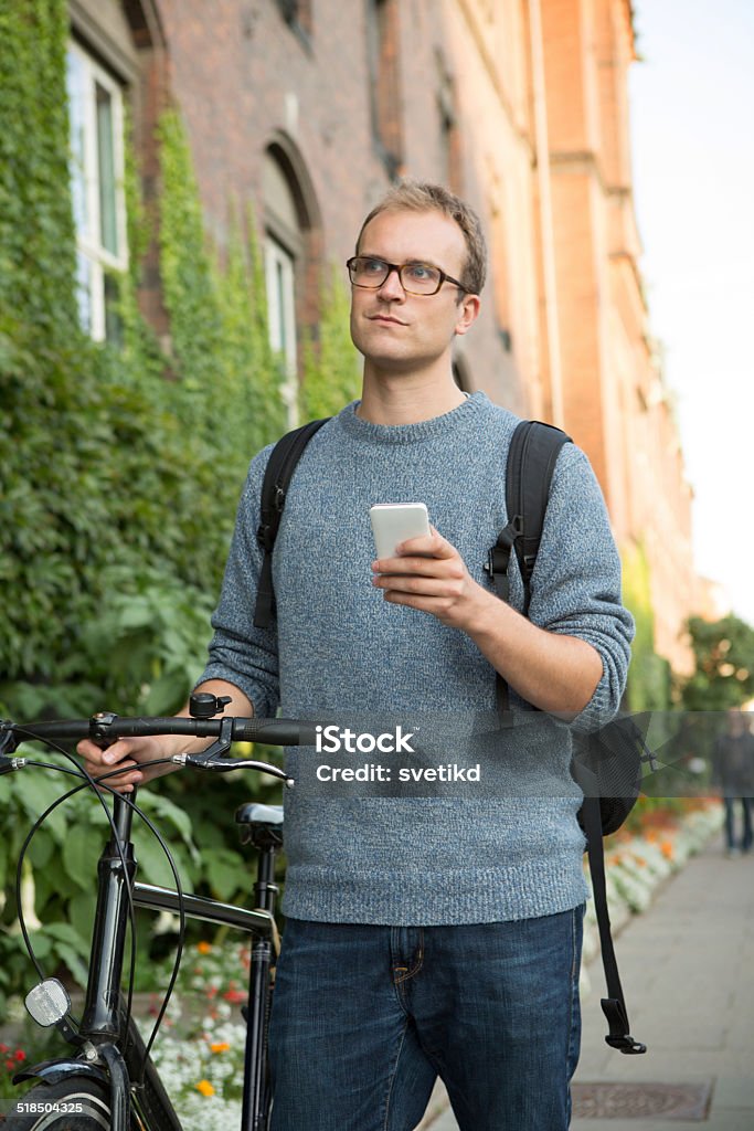 Young man on city street with bicycle. Young man on city street with bicycle using smart phone. 20-29 Years Stock Photo