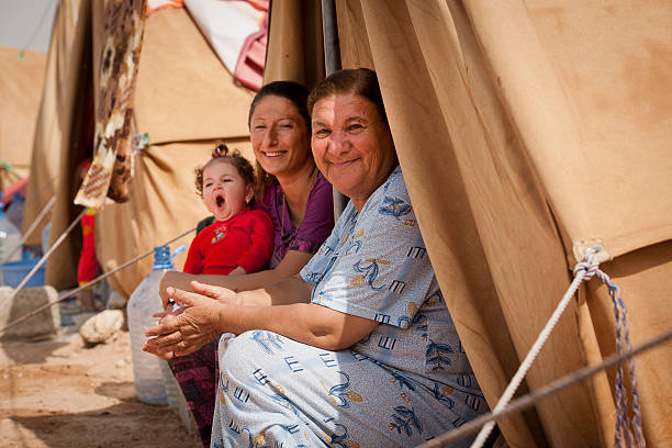 Refugees in front of their tent Erbil, Kurdistan, Iraq - October 04, 2014: IDP camp in Erbil in the middle of the city. On this sport compound are living refugees from Mosul and Karakosh. The refugees living in very poor conditions without water and bathrooms. Grandma with daugher and granddaughter. iraqi kurdistan stock pictures, royalty-free photos & images