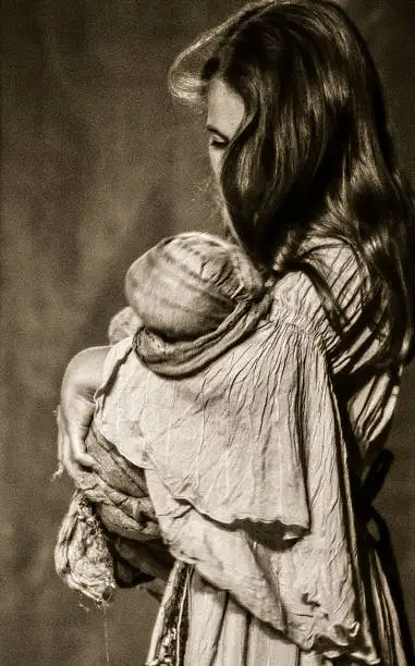 Girl looking tenderly to her doll, dressed for a play, antique style, sepia colors