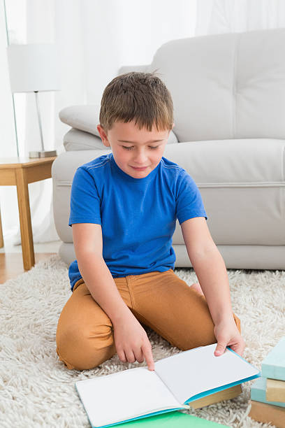 istock Little boy sitting on the floor reading storybook 518522383
