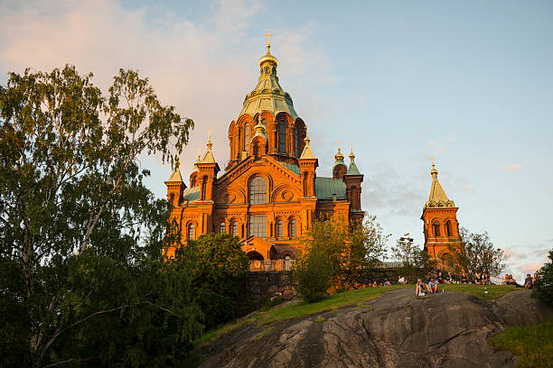 Helsinki, Finland - July 5, 2015: People sit on a hill in front of Uspenski Cathedral to watch the sunset in Helsinki, Finland. The cathedral is an orthodox church.