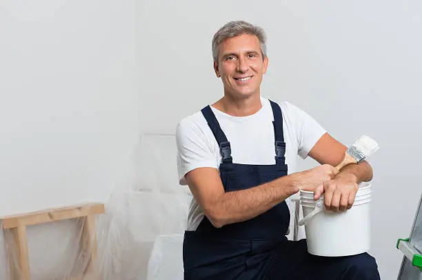 Portrait Of Happy Mature Painter With Stepladder And Paint Bucket