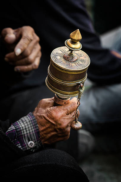 руки в тибетский буддийский с его молитвы колесо - prayer wheel стоковые фото и изображения