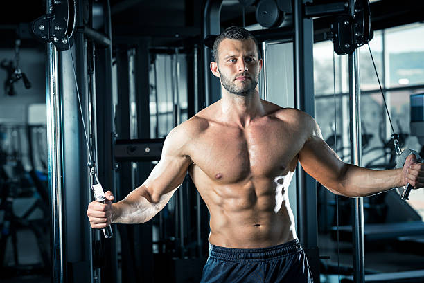 hombre haciendo cable exclusión en el gimnasio - chest fly fotografías e imágenes de stock