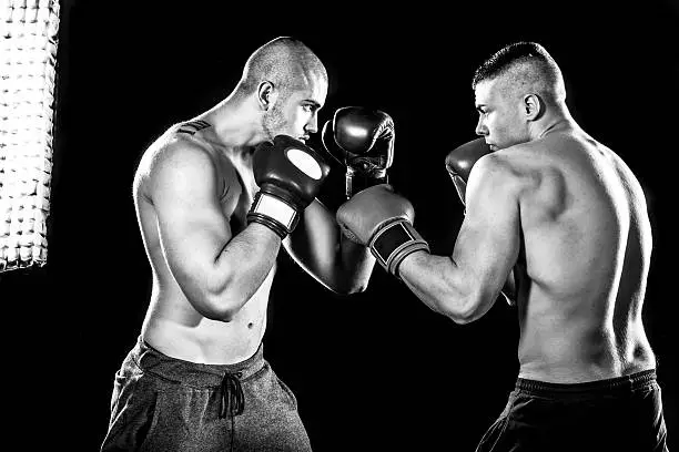 Two professional boxer isolated on black background, black and white photography, in studio low key with flash light