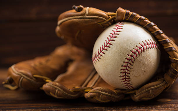 istock Leather baseball glove and ball on a wooden bench 518526464