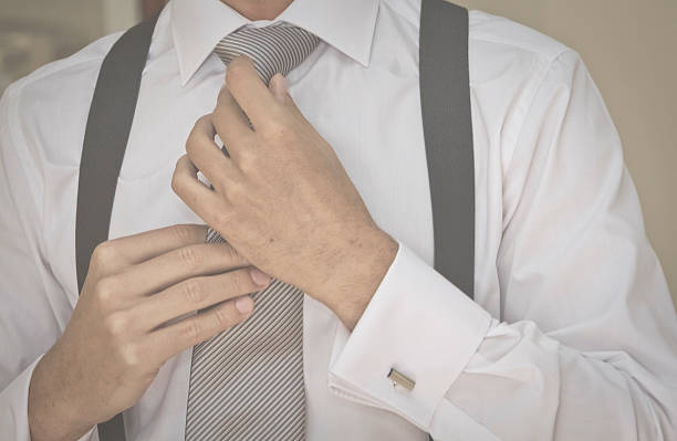 istock Man or bridegroom adjusting a grey tie with his hands 518527408