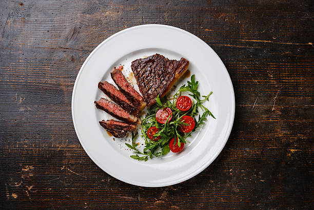 istock Sliced steak Striploin and salad with tomatoes and arugula 518527596