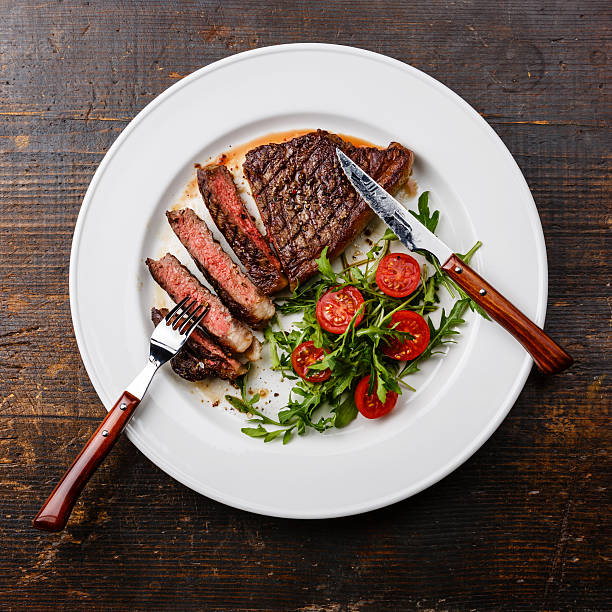 istock Sliced grilled steak Striploin and salad with tomatoes and arugula 518527602