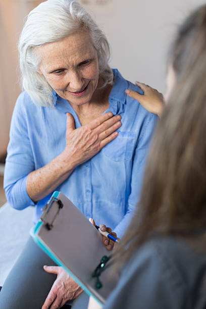 старший женщина's's визита к врачу-исследователю для боль в груди - nurse illness doctor heart disease стоковые фото и изображения
