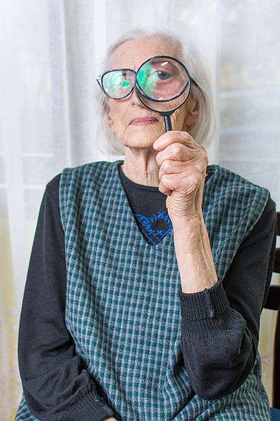 istock Senior woman looking through magnifying glass 518528834