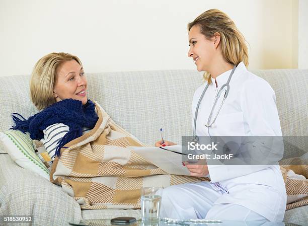 Cheerful Doctor Helping Female Pensioner With Flue At Home Stock Photo - Download Image Now