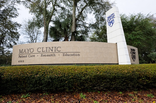 Jacksonville, Florida, USA - March 18, 2016: Looking up at Mayo Clinic sign at 4500 San Pablo Road in Jacksonville, Florida. Sign on the south side of the Mayo Boulevard entrance to the Mayo Clinic campus. Sign highlights patient care, research, and education.