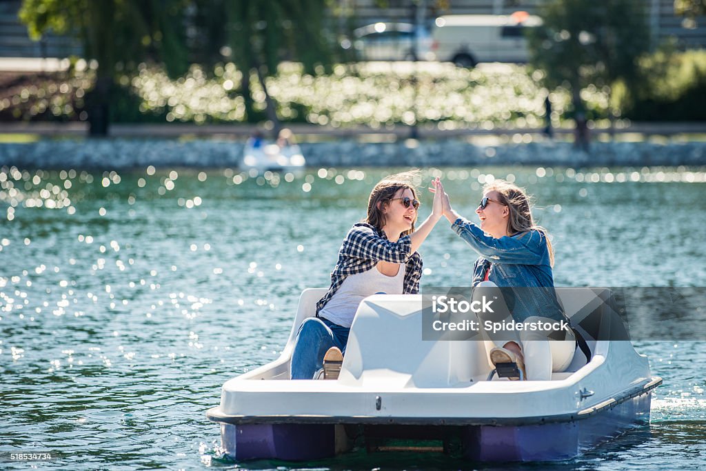 Teenage Girls on a Paddle Boat Two teenage girls giving high fives  on a paddle boat in a lake. Pedal Boat Stock Photo