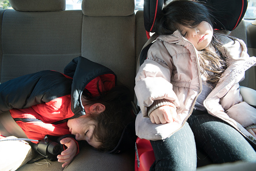 Little girl and boy, brother and sister, sleeping in the carseat in the car