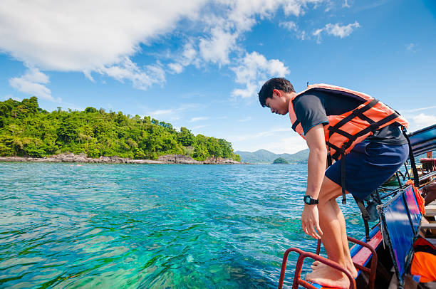 istock Man jumping off the boat into the ocean 518550174