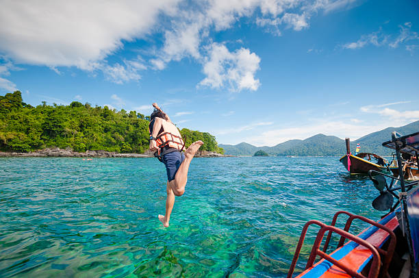 istock Man jumping off the boat into the ocean 518550322