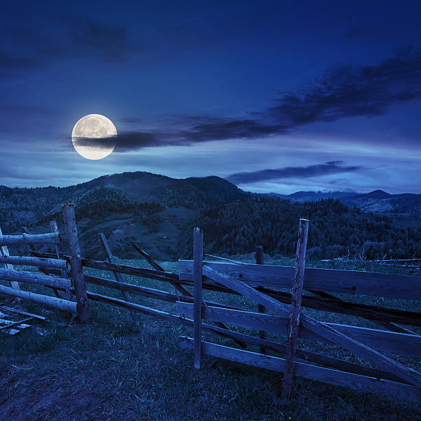 istock fence on hillside meadow in mountain at night 518551177