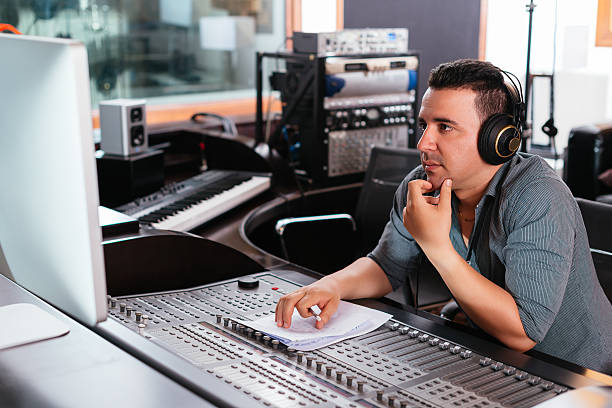 Working at mixing panel Hispanic sound engineer working at mixing panel in the recording studio sound technician stock pictures, royalty-free photos & images