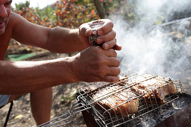 Man seasoning pork chops with pepper at the picnic