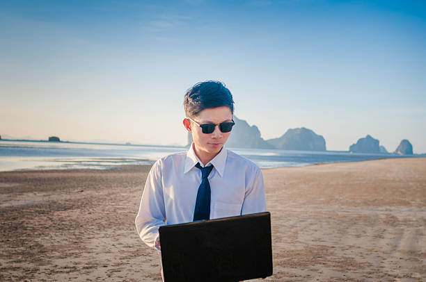 istock Business man working with laptop and smartphone beach background 518557584