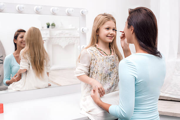 istock Mother and little daughter applying makeup 518560474