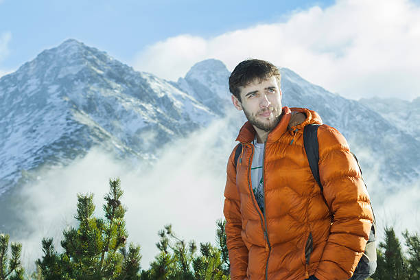 Bello alpinista in posa su uno sfondo di neve paesaggio roccioso - foto stock