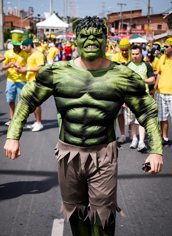 Fortaleza, Brazil - 4 July 2014: A Brazilian soccer fan dressed as the alter-ego of the footballer Givanildo Vieira de Sousa, more popularly known as Hulk. In the background are fellow Brazilian football fans making their way to the Castelao stadium to watch their team face Colombia in the 2014 Soccer World Cup.