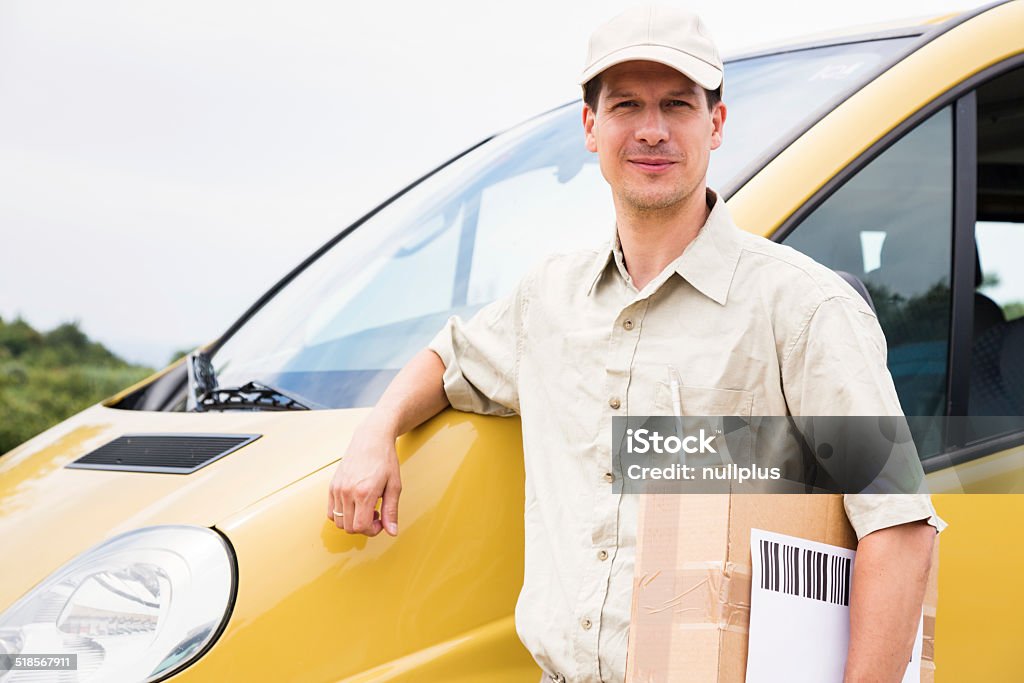 messenger with parcel standing next to his delivery van messenger with parcel standing next to his delivery van. 30-39 Years Stock Photo